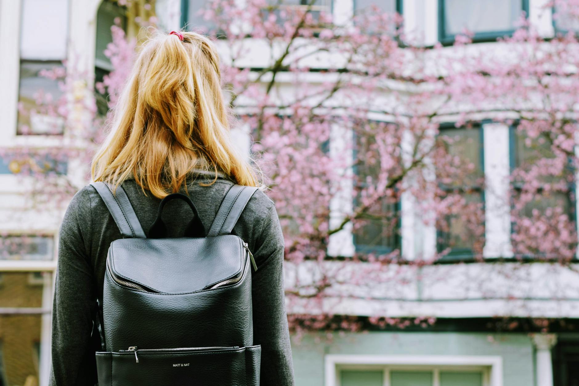 woman wearing backpack standing in front building