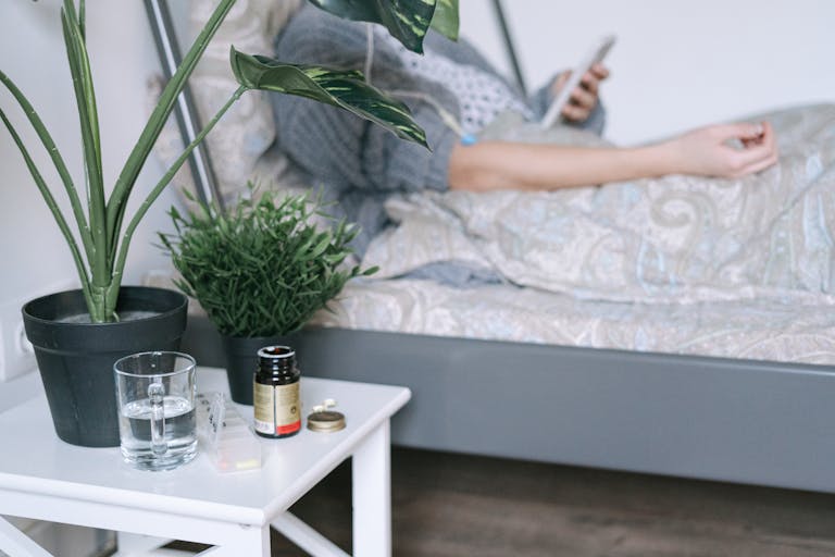 A patient resting in a hospital bed with care essentials nearby, while getting sick when travelling solo