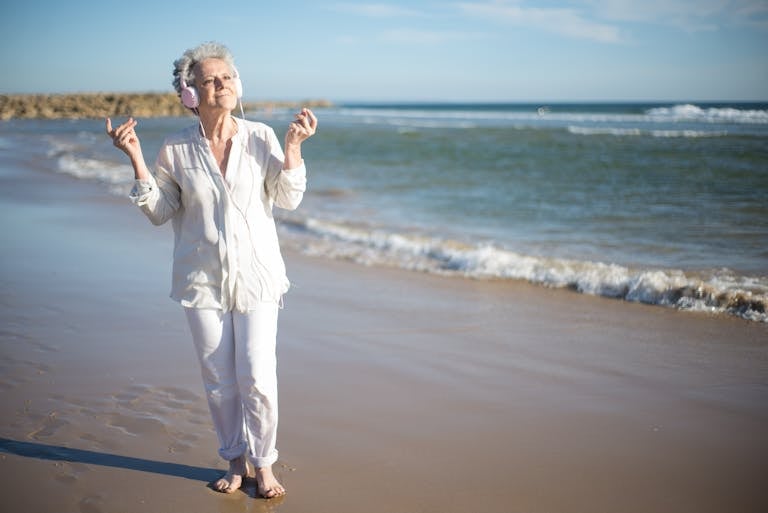 How old is too old to travel solo? This Senior woman is enjoying music on a sunny beach in Portugal.