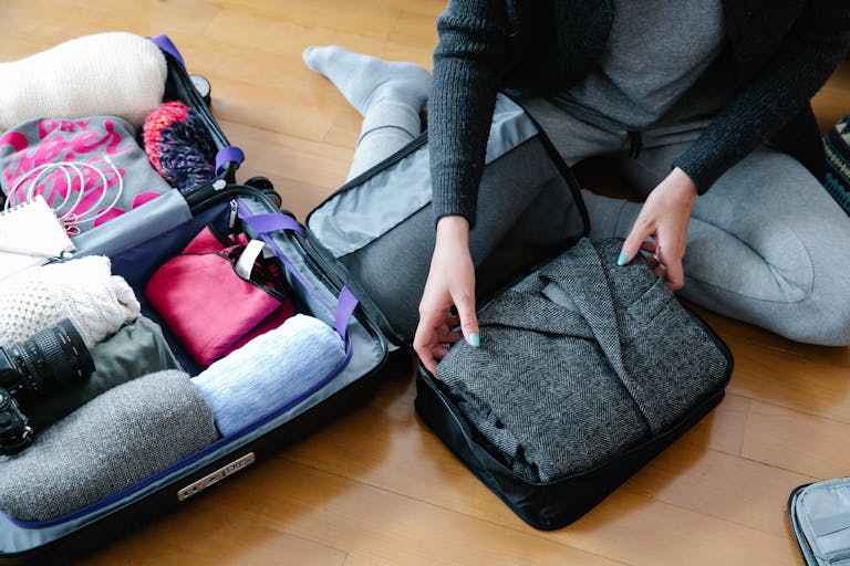 Woman organizes clothing and camera gear in a suitcase and wondering what to pack for Samana